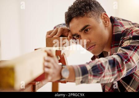 Holz, Bauarbeiten und Projekt mit einem Zimmermann, der Heimwerker mit Sandpapier in seinem Haus für Bauarbeiten, Renovierungen und Renovierungen ist. Zimmerei, Bauunternehmer und Wartung mit einem jungen Handwerker Stockfoto