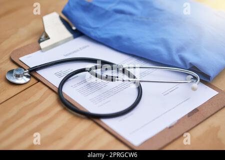 Diagnostische Grundlagen. Nahaufnahme eines Stethoskops, das mit einem gefalteten Krankenhauskleid auf einem Arztkittel liegt. Stockfoto