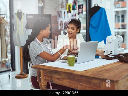 Zwei junge Modedesigner, die an einem Laptop arbeiten. Stockfoto