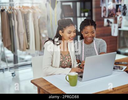 Alles beginnt mit einem Design. Zwei junge Modedesigner arbeiten an einem Laptop. Stockfoto