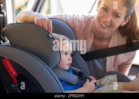 Die Sicherheit meiner Kinder ist sehr wichtig. Porträt einer Mutter, die ihren Jungen sicher auf einem Autositz befestigt. Stockfoto