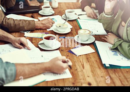 Einige neue Geschäftsentwürfe zu bearbeiten. Nahaufnahme von Geschäftsleuten, die in einem Büro Papierkram durchsuchten. Stockfoto