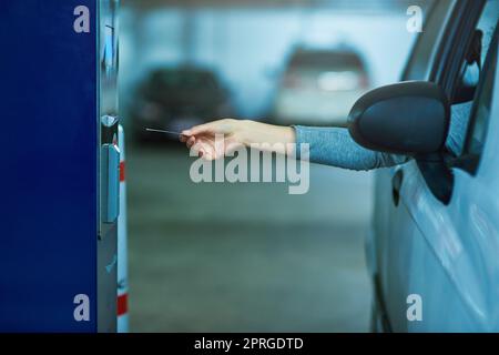 Keine darf passieren, es sei denn, die Maut wird bezahlt. Ein nicht erkennbarer Fahrer, der ein Ticket in eine Parkuhr einführt. Stockfoto