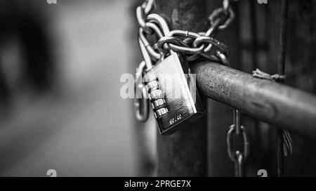 Vorhängeschloss in schwarz-weiß an einer Kette. Verriegelt und verriegelt. Geheimnisvoll und sicher. Stockfoto