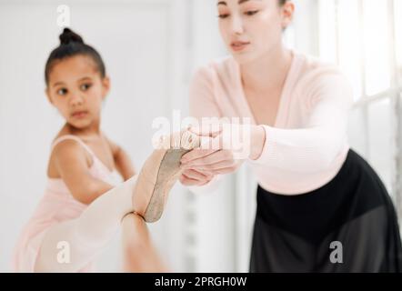 Zeig auf die Zehen. Ein kleines Mädchen, das Ballett mit ihrem Lehrer in einem Tanzstudio praktiziert Stockfoto