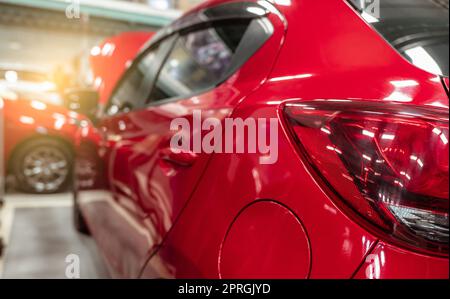 Rückansicht eines roten SUV, der in der Autoherstellung geparkt ist. Rotes Auto in der Werkstatt der Tankstelle. Fahrzeug in der Werkstatt. - Das ist ein Cleseup-Licht. Rotes Auto in der Garage für Reparatur- und Wartungsservice. Stockfoto