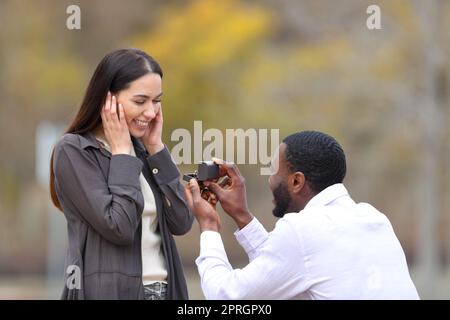 Heiratsantrag eines glücklichen interracial Paares in einem Park Stockfoto