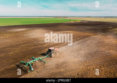 Luftaufnahme. Pflügen Des Traktors. Beginn Der Landwirtschaftlichen Frühjahrssaison. Kultivator, gezogen von Einem Traktor in ländlicher Ackerlandschaft. Staub Steigt Unter Dem Pflug Auf Stockfoto