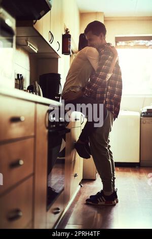 Sie haben alles, was ich je brauchte. Ein liebevolles junges Paar, das einen romantischen Moment in der Küche teilt. Stockfoto