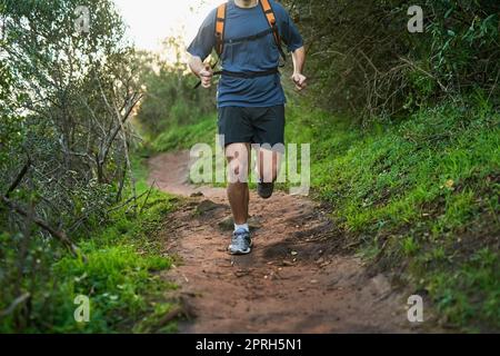 HES macht Strecken. Ein nicht erkennbarer männlicher Athlet, der auf einem Waldweg läuft. Stockfoto