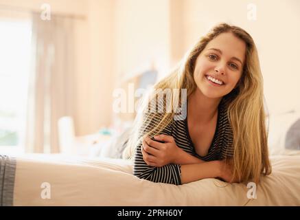 Wenn ich mich wohl gefühlt habe, bin ich glücklich. Porträt einer attraktiven jungen Frau, die auf ihrem Bett liegt. Stockfoto