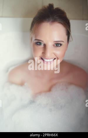 Wie ich mich nach einer langen Woche gerne ausruhen möchte. Porträt einer attraktiven jungen Frau, die sich in der Badewanne entspannt. Stockfoto