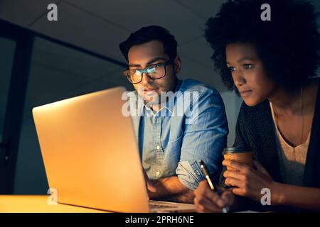 Planen des nächsten strategischen Umzugsvorauszues. Zwei Kollegen arbeiten spät an einem Laptop in einem Büro. Stockfoto