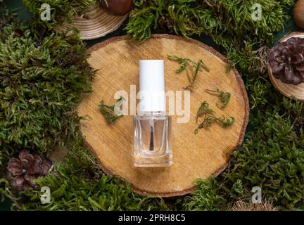 Nachfüllbare Flasche mit Bürstenverschluss auf Holzstück zwischen grünem Moos, Nagelmodell Stockfoto