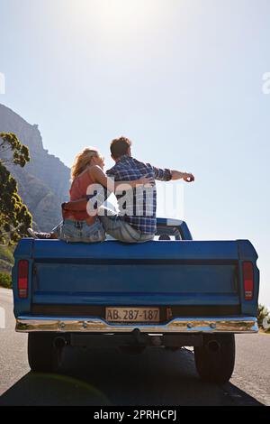 Ein junger Mann, der mit seiner Freundin auf eine Reise unterwegs ist, zeigt auf etwas. Stockfoto