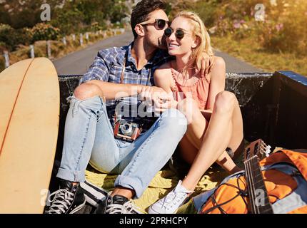 Die größten Geschichten bilden sich auf der offenen Straße. Ein junges Paar, das sich auf einer Autoreise auf dem Rücken eines Pickup-Trucks entspannt. Stockfoto