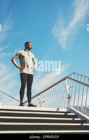 In Topform bleiben. Ein junger sportlicher Mann, der draußen steht. Stockfoto