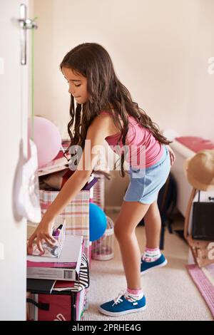 Das geht hier. Ein fokussiertes junges Mädchen, das Spielzeug verpackt und ihr Zimmer zu Hause aufgeräumt hat. Stockfoto