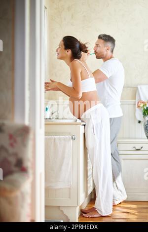 Gemeinsam durch den Alltag gehen: Ein Mann und eine Frau putzen sich im Badezimmer die Zähne zusammen. Stockfoto