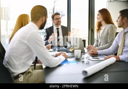 Überprüfung der Ziele aus der vorherigen Sitzung. Ein Team von Führungskräften, das eine formelle Sitzung in einem Sitzungssaal hat. Stockfoto