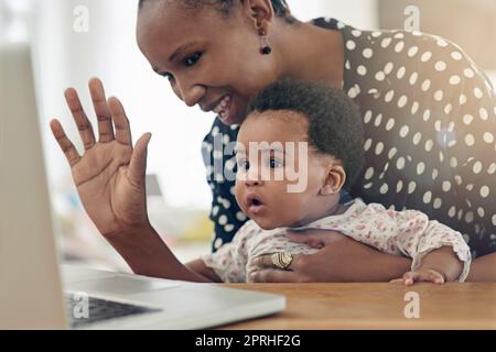 Eine Mutter und ihr kleines Mädchen sitzen vor einem Laptop. Stockfoto