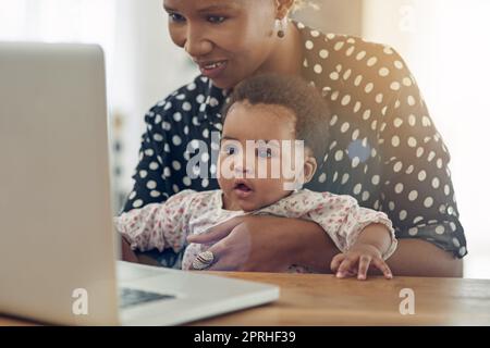 Entdecken Sie die Welt der Technologie. Eine Mutter und ihr kleines Mädchen sitzen vor einem Laptop. Stockfoto