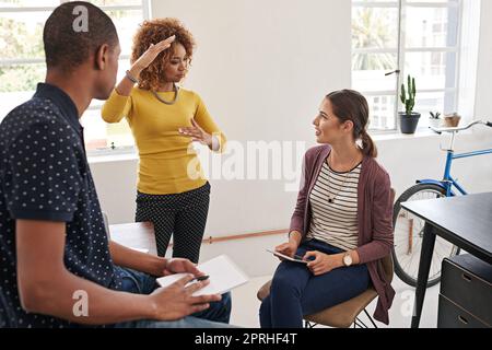 Sie fördern den Austausch von Ideen in diesem Büro. Eine Gruppe von Kollegen, die in einem modernen Büro ein informelles Treffen abhalten. Stockfoto