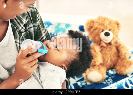 Lecker, nicht so. Eine Mutter gibt ihrem kleinen Jungen eine Flasche. Stockfoto