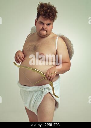 Hes bringt die Liebe dieses Valentines. Ein übergewichtiger Mann, der als Cherub mit Pfeil und Bogen gekleidet ist Stockfoto