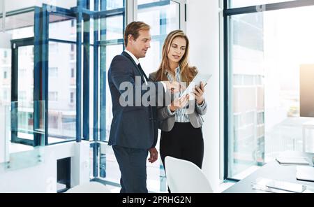 Zusammenarbeit bei dem bisher größten Projekt. Zwei Geschäftsleute diskutieren etwas auf einem digitalen Tablet. Stockfoto