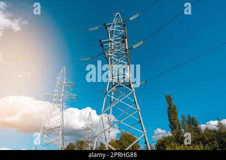 Niedriger Winkel von Hochspannungstürmen und Elektrokabeln vor dem sonnigen blauen Himmel Stockfoto