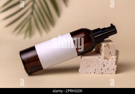 Glaskosmetik, eine Pumpflasche auf Stein in Hellbeige mit Palmenblatt. Label Modell Stockfoto