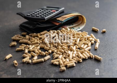 Holzpellets, Biokraftstoff mit Euro-Geld. Ökologischer Brennstoff aus Biomasse. Erneuerbare Energiequelle. Stockfoto