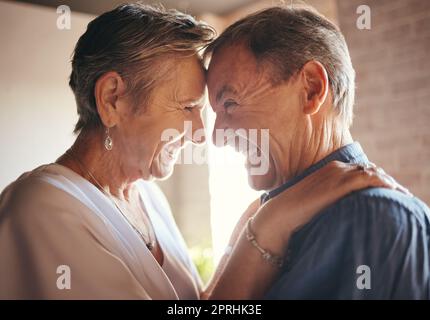 Lieben, glücklich und lachen Ältere Paare umarmen und binden sich in ihrem Zuhause zusammen, fröhlich und teilen einen lustigen Witz. Humor, Fürsorge und Zuneigung durch einen älteren Mann Stockfoto