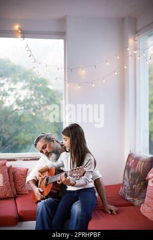 Ein kleines Mädchen, das mit ihrem Großvater Gitarre spielt Stockfoto