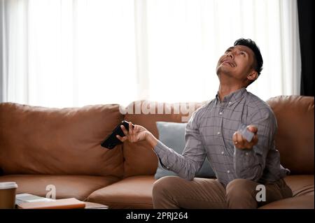 Schockierter und weinender asiatischer Millennials, der ein finanzielles Problem oder Probleme mit seiner mobilen Banking-Anwendung hat. Bankrott, Pleite Stockfoto