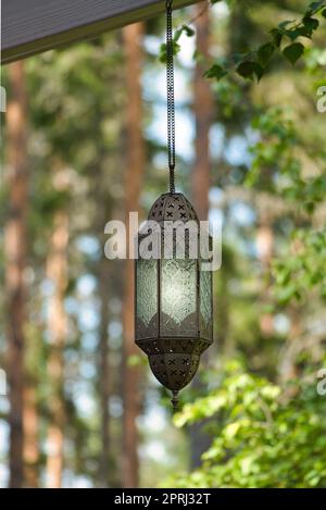 Die Lampe wird vor einem Wald aus Metall und Glas auf einer Piste aufgehängt. Beleuchtet. Stockfoto