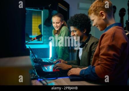 Tonproduzent mischt Musiktitel mit Kinderband auf Laptop-Computer im Aufnahmestudio Stockfoto