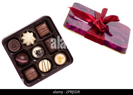 Nahaufnahme einer Schachtel mit feinen Schokoladenbonbons in einer wunderschönen Plastikbox isoliert auf weißem Hintergrund. Überraschungsgeschenk zum Valentinstag oder zu anderen festlichen Anlässen. Makro. Stockfoto