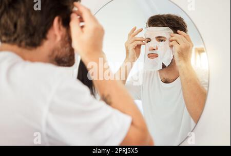 Hautpflege, Gesicht und Gesichtsmaske auf Mann auf Spiegel im Heim-Badezimmer. Junger Mann mit Selbstpflege, Schönheit oder kosmetische Reinigung für die Gesundheit der Haut und Wellness Stockfoto