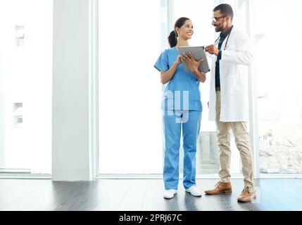 Eine zweite Meinung zu bekommen, schadet nicht. Zwei junge Ärzte mit einem digitalen Tablet in einem modernen Krankenhaus. Stockfoto