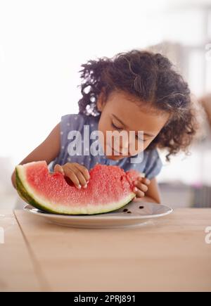 So...many...seeds. Ein süßes kleines Mädchen, das Wassermelone an einem Tisch isst Stockfoto