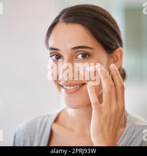 Hält ihre Haut in perfektem Zustand. Eine schöne Frau, die Feuchtigkeitscreme auf ihr Gesicht Stockfoto