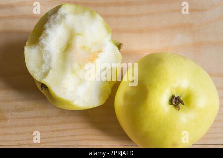 Reif Grün gebissen und ganzen Apfel auf einer hölzernen Hintergrund. Stockfoto