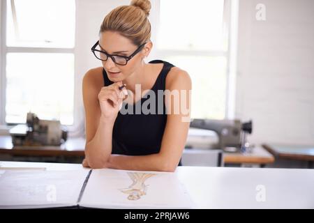 Die neuesten Moden entwerfen. Eine attraktive junge Frau, die an einem Kleidungsdesign arbeitet Stockfoto