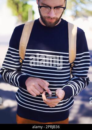 Der Inbegriff von Geek trifft auf Hip trifft auf den modernen Hipster. Ein hübscher junger Hipster draußen mit Brille Stockfoto