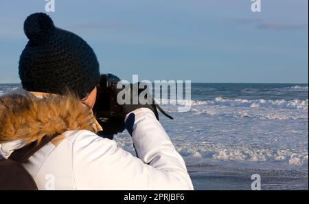 Junge Frau fotografiert Wellen auf dem Pazifischen Ozean auf der Kamtschatka-Halbinsel Stockfoto