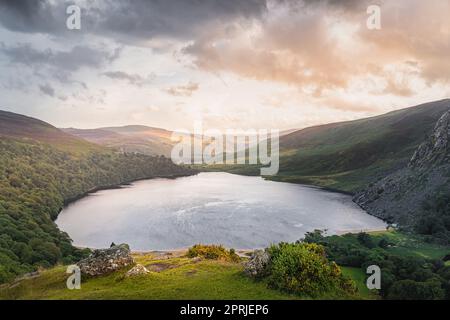 Schöner und dramatischer Sonnenuntergang am Lough Tay, genannt Guinness Lake, liegt im tiefen Tal und ist von den Wicklow Mountains, Irland, umgeben Stockfoto