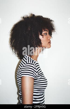 Das Profil der lockigen Perfektion. Profil einer attraktiven jungen Frau, die vor grauem Hintergrund im Studio posiert. Stockfoto