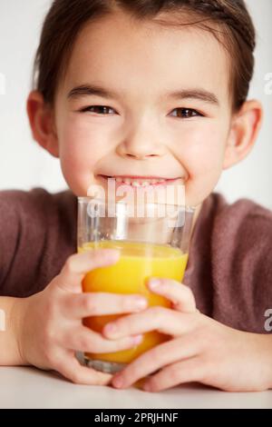 Frisch gepresster Orangensaft. Nahaufnahme eines bezaubernden kleinen Mädchens, das ein Glas Orangensaft trinkt Stockfoto